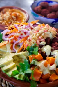 A beetroot falafel rice bowl sits with salad and other toppings.
