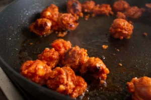some pieces of chorizo are cooked in a frying pan