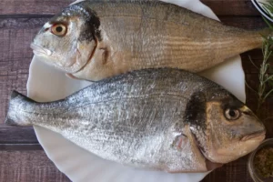 2 whole bream sit on a white plate
