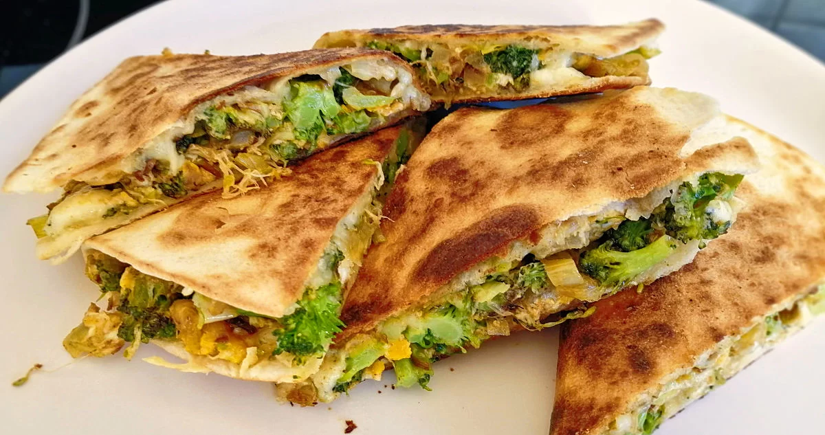 Leek, brocolli, and blue cheese quesadillas sit on a white plate