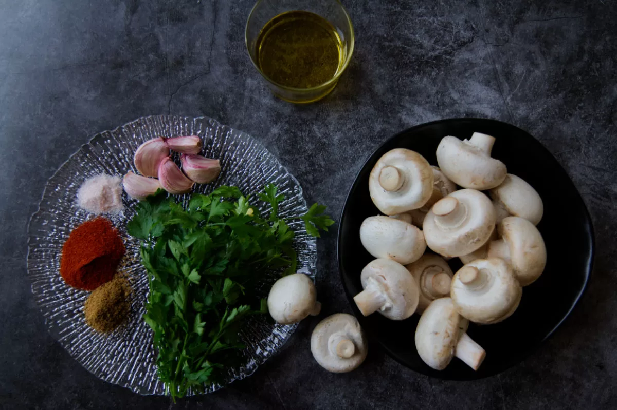 ingredients for making Spanish garlic mushrooms are laid out on a table.