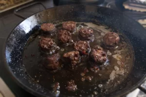 some slices of morcilla sausage cook in some oil in a pan.