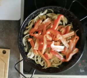strips of pepper cook with some diced onion