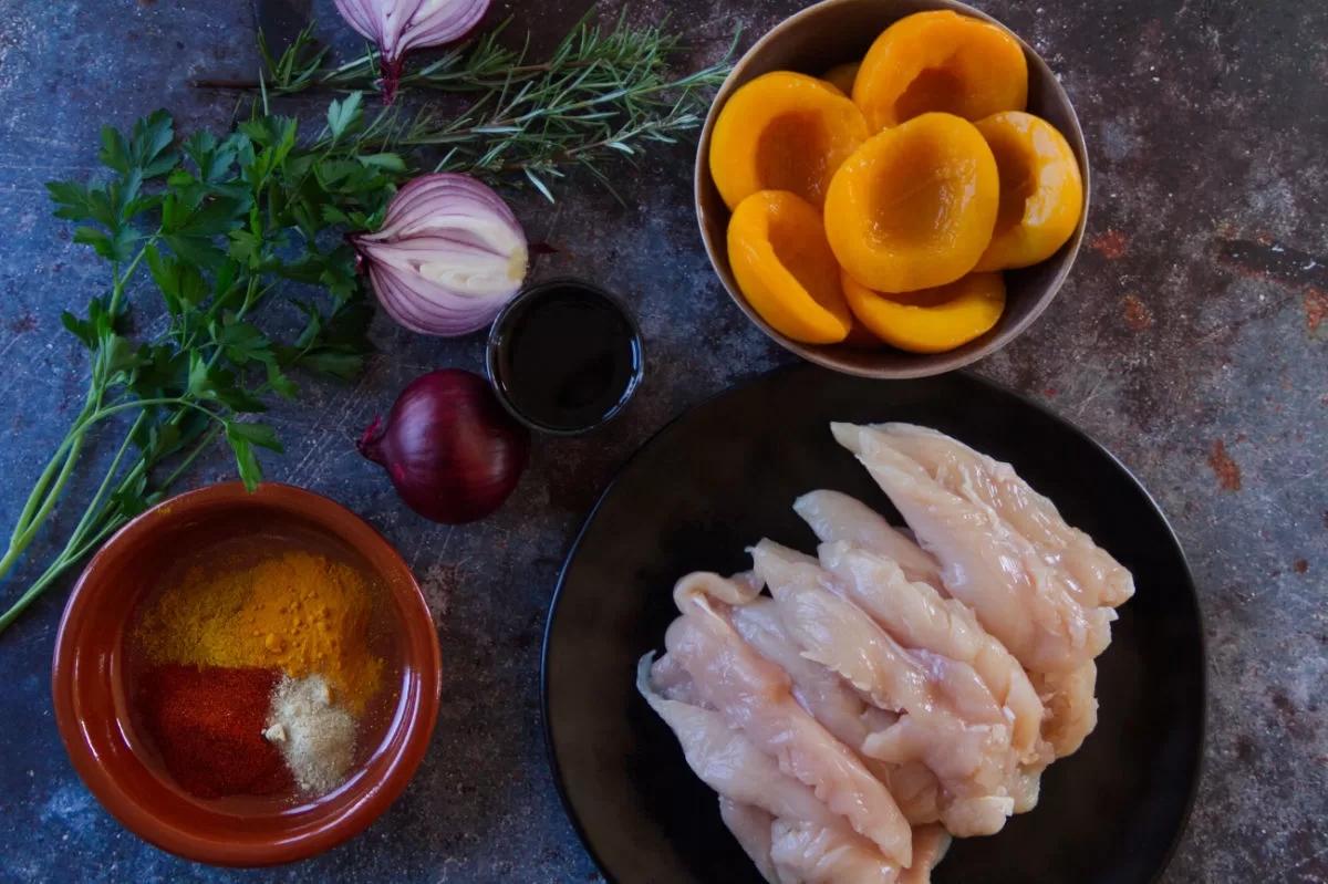 ingredients for making chicken with peaches and sherry is laid out on a kitchen counter.