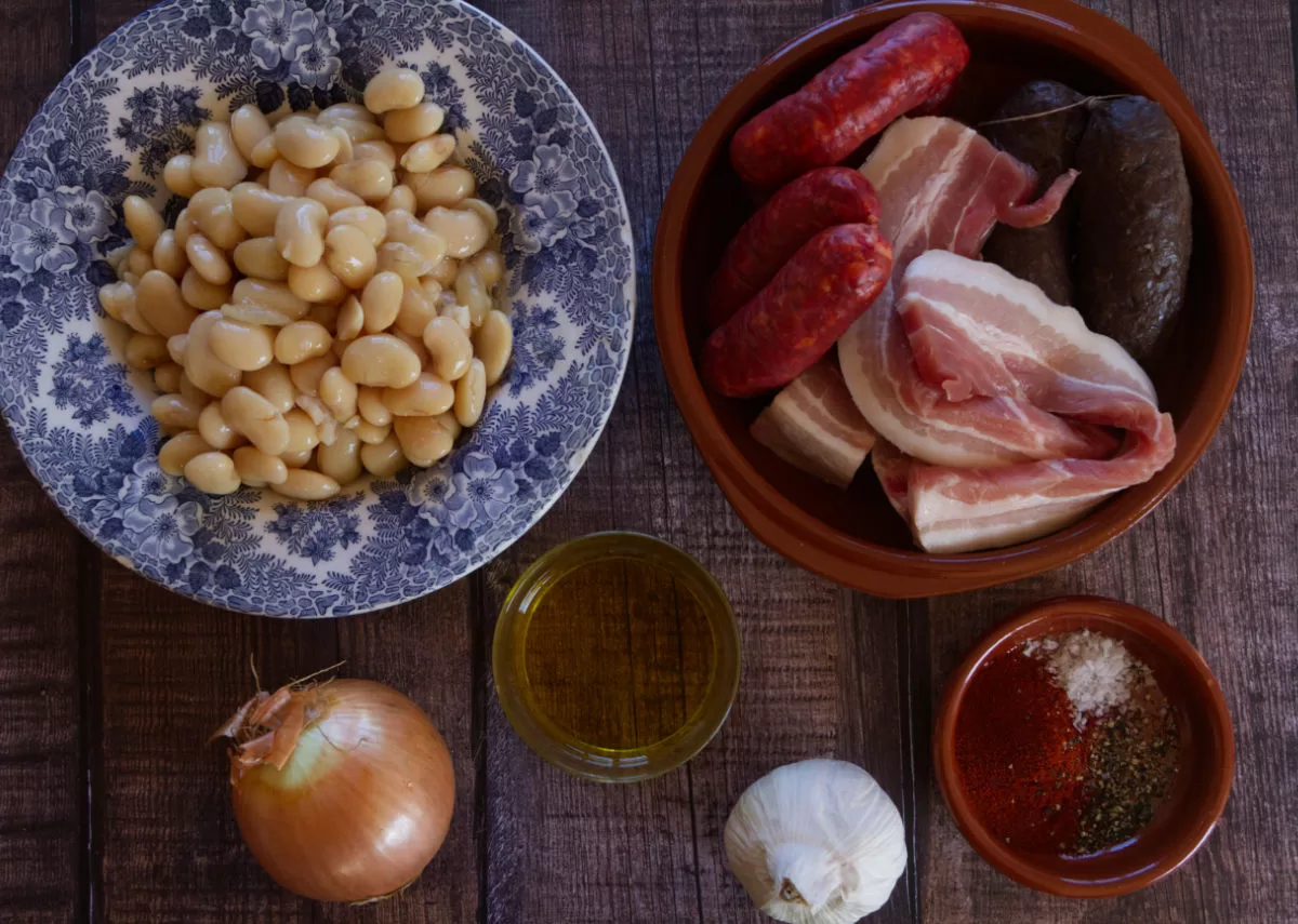 Ingredients for making traditional Fabada Asturiana are laid out on a kitchen counter.