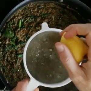 lemon juice is squeezed into a pot of lentil stew