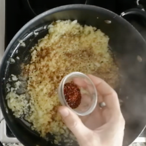 Spices are added to a large pot of sauteed onions.