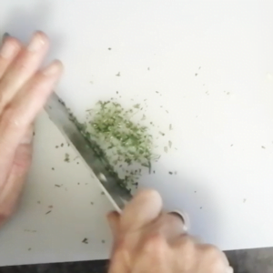 Chopped rosemary on a white chopping board