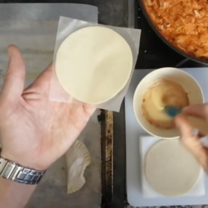 aperson holds an empanada disk in the open palm of their hand.