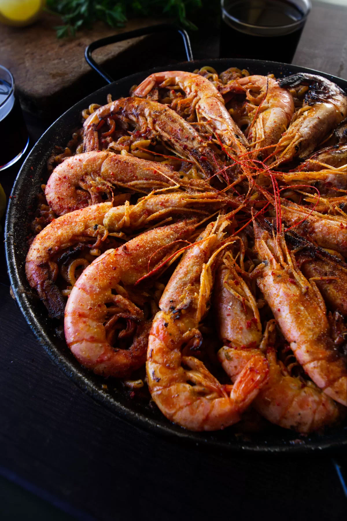 a large pan of fideua marisco is topped with large shrimp