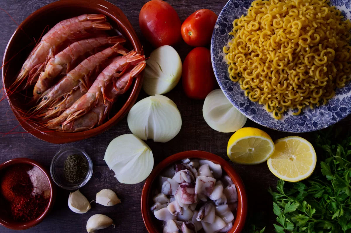 ingredients used to make fideua marisco are laid out on a kitchen table. 