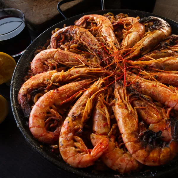 A large pan of Spanish fideua with marisco is topped with large cooked shrimp
