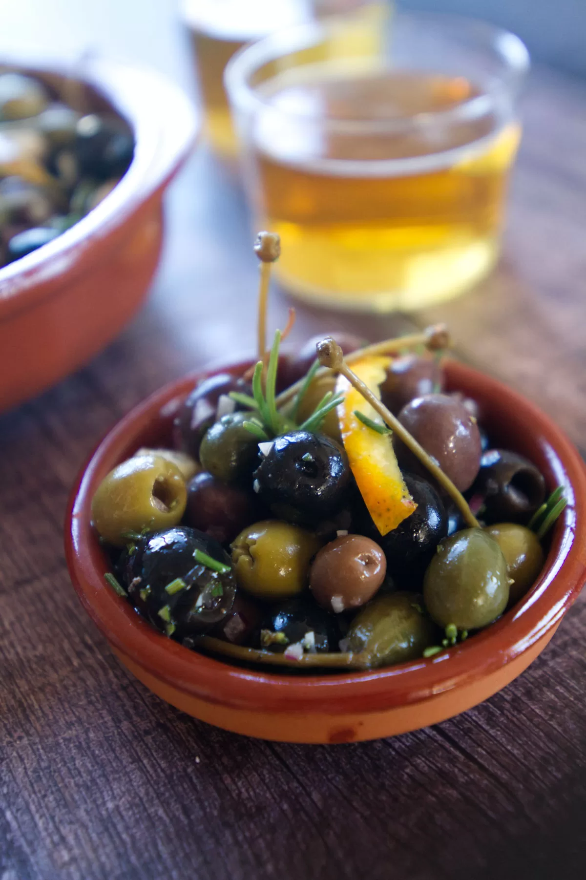 a tapas serving of marinated olives sits beside a glass of beer