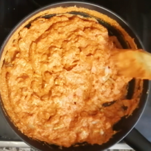 Romesco sauce and fish are added to a pan.