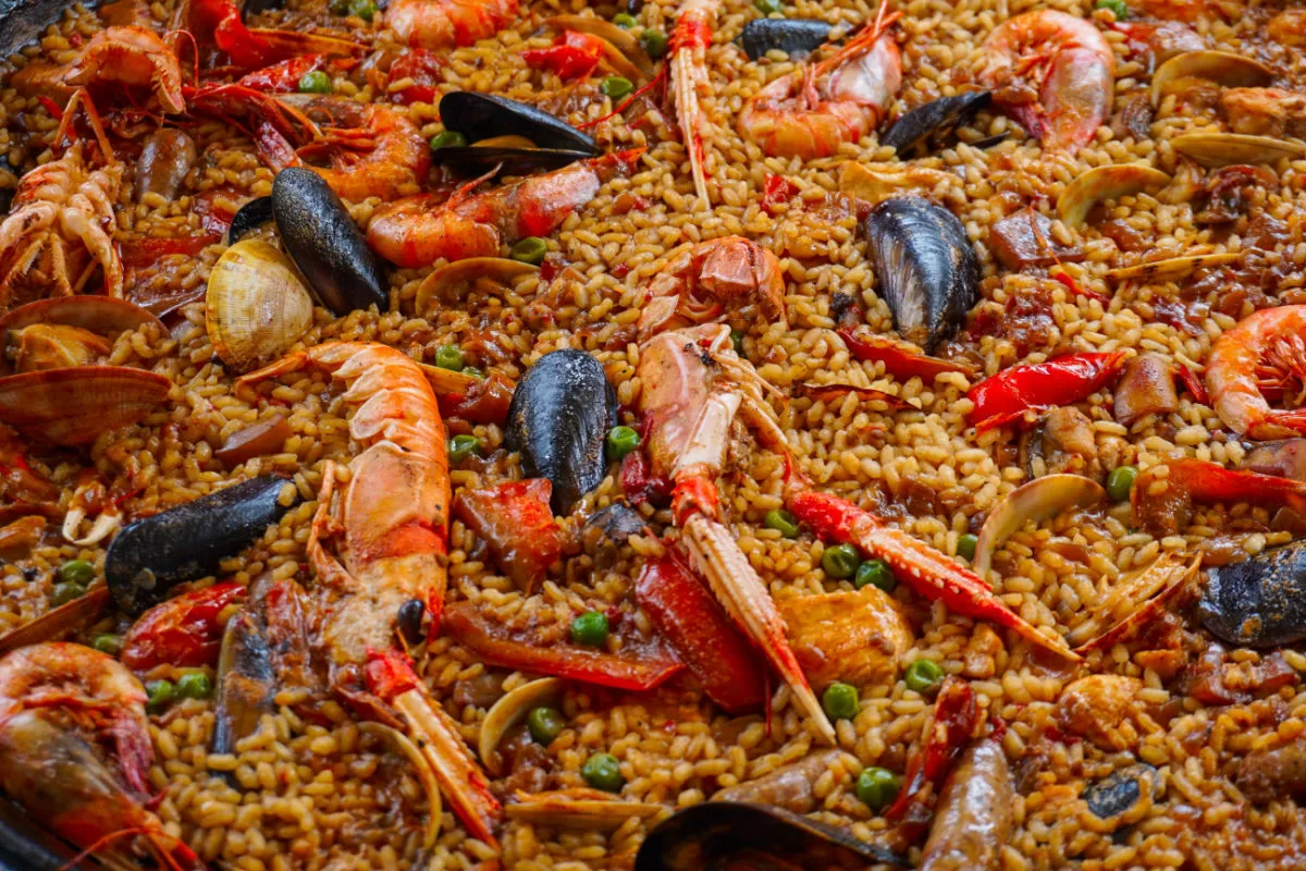 A pan of seafood paeella sits topped with cooked seafood.