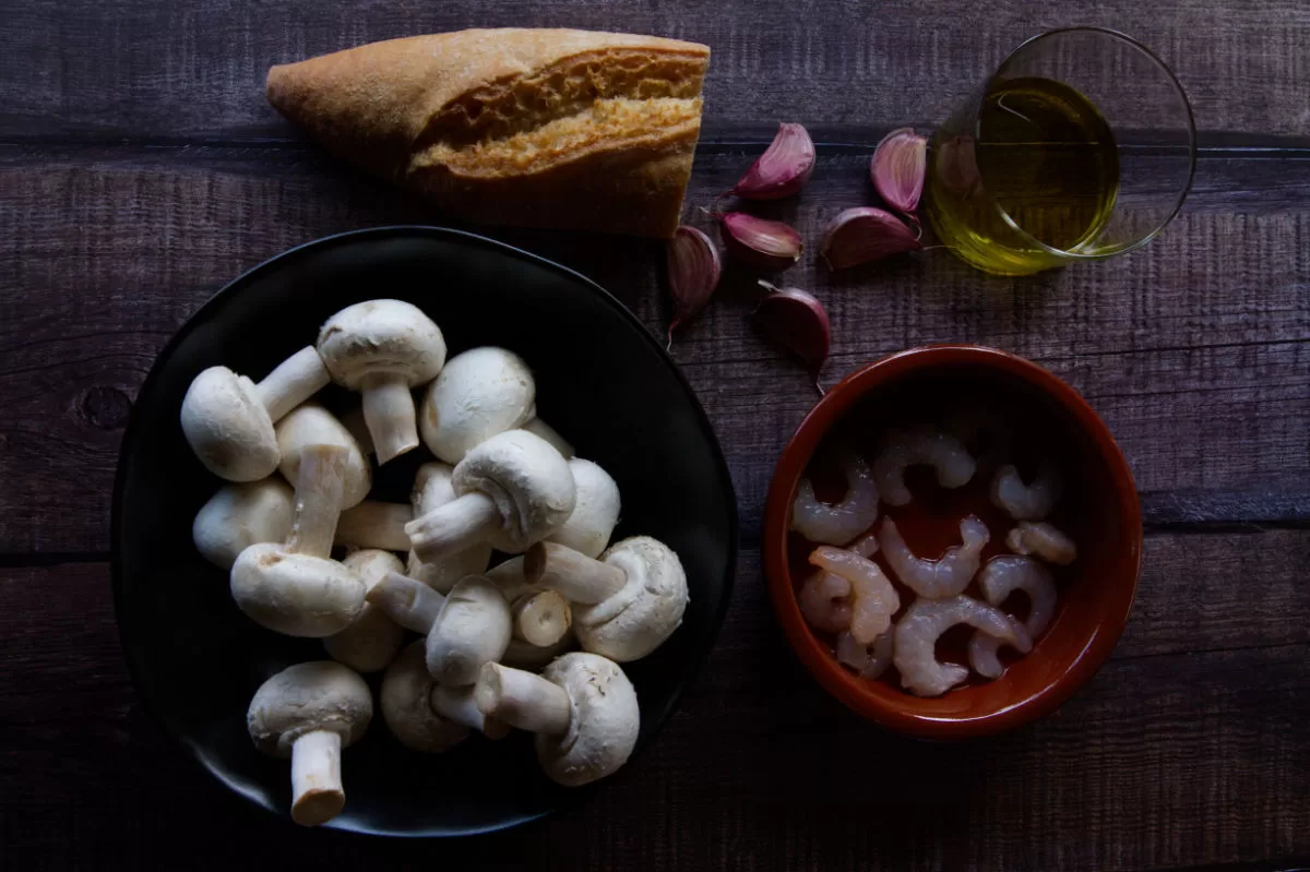 Ingredients used to make mushroom and shrmip tapas are laid out on a counter.