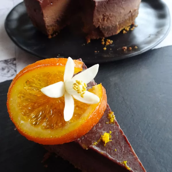 A slice of baked Orange Chocolate cheesecake sist beside a whole cake