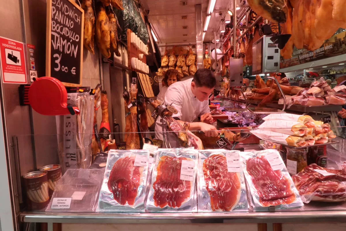 a man slices ham in a small ham shop