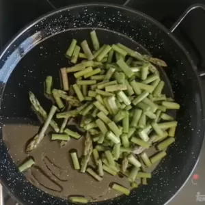 some asparagus is sauteed in a frying pan