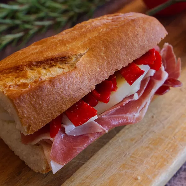A baguette sandwich with serrano ham, Manchego cheese, and picollo peppers.