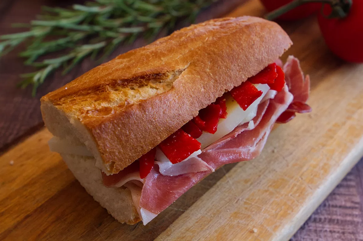 A baguette sandwich with serrano ham, Manchego cheese, and picollo peppers.