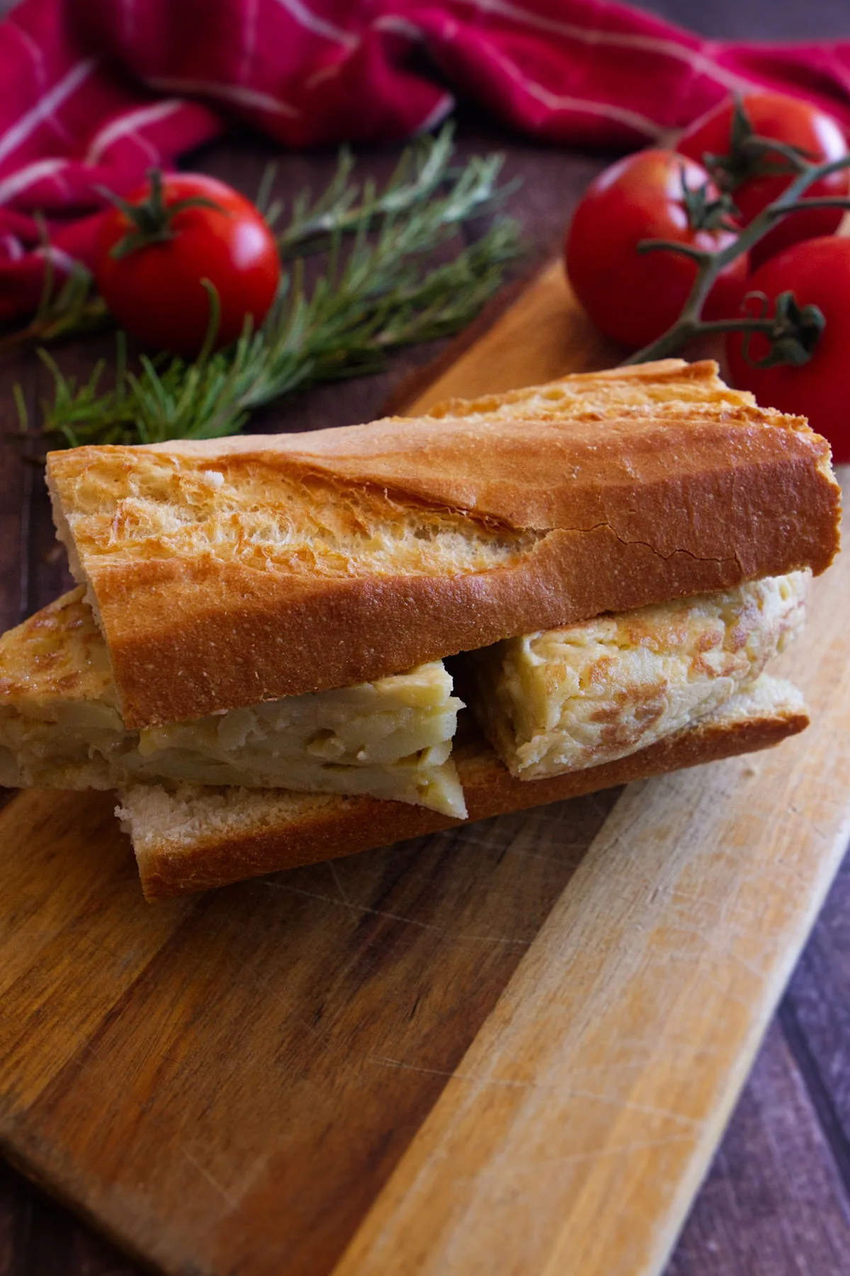 a portion of bocadillo de tortilla is served on a wooden chopping board.