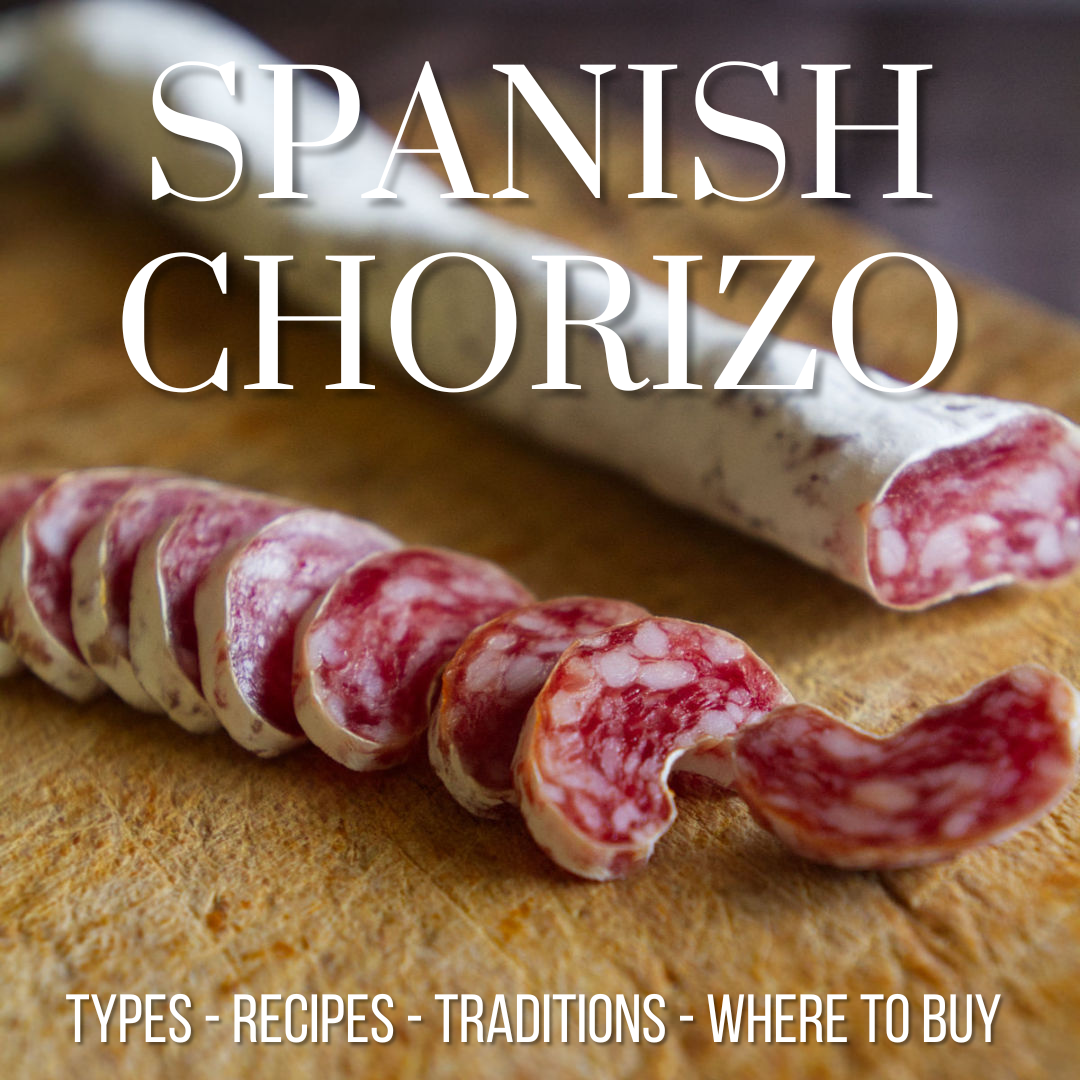 A cured Spanish chorizo with a white skin is sliced into small pieces on a rustic chopping board.