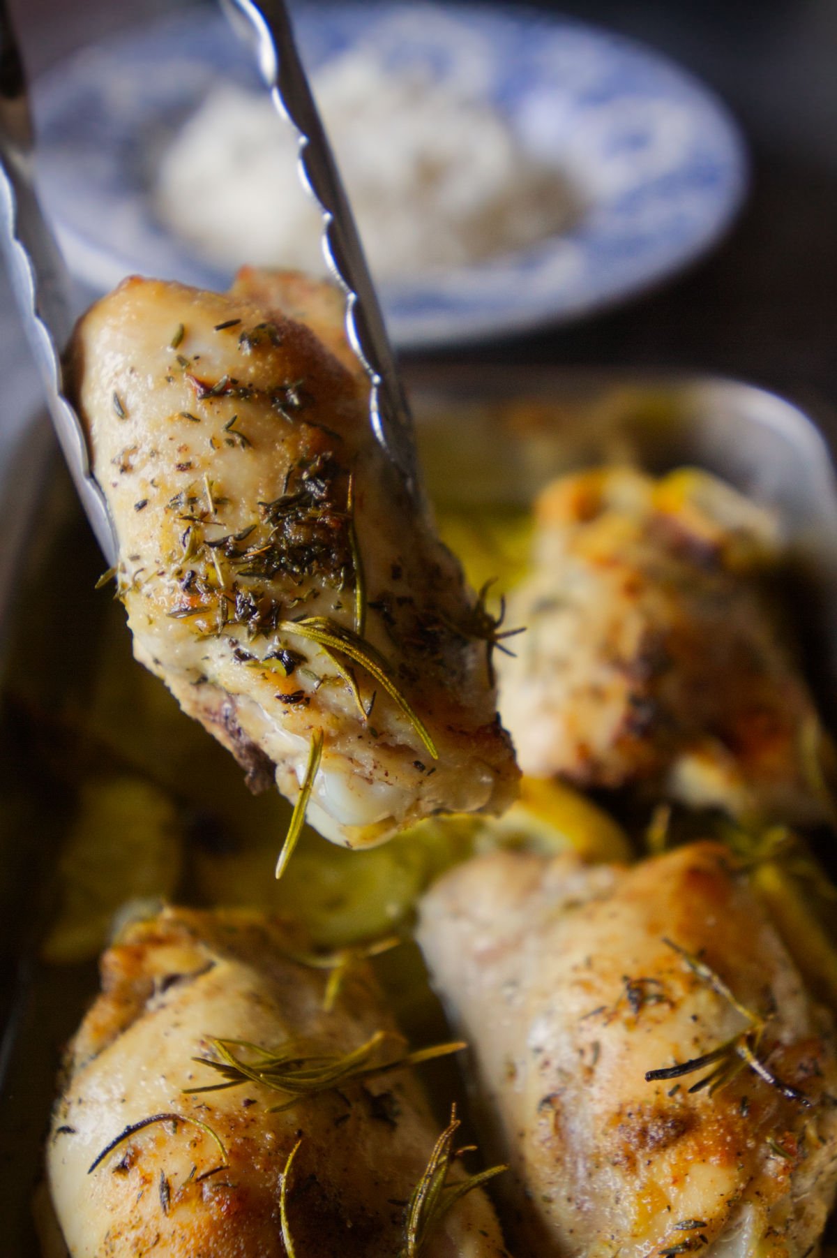 A piece of lemon and herb chicken is lifted from a pan. 