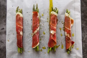 some uncooked asparagus spears wrapped in Serrano ham