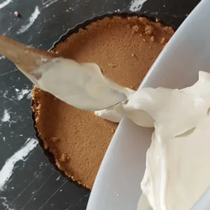 A cheesecake mixture is added to a base in a tart pan.