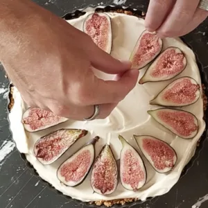 Slices of fresh fig are arranged on top of a cheesecake.
