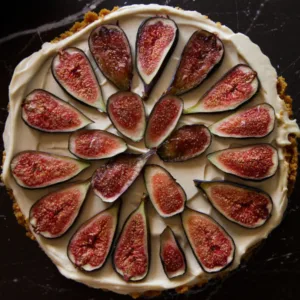 a fig and vermouth cheesecake sits on a black marble counter.