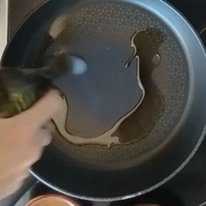 some oil is added to a non-stick frying pan.