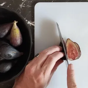 A fig is sliced on a chopping board.