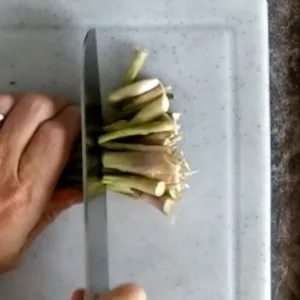 The ends of a bunch of asparagus spears is trimmed.