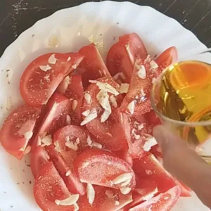 A plate of tomato slad is drizzled with olive oil.