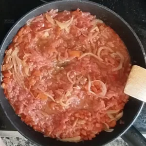 sauteed tomatoes in a pan with some ham, red pepper and onion.