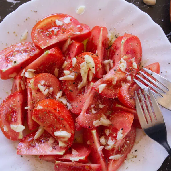 A plate of Spanish tomato salad garnished with garlic and olive oil.