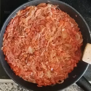Some tomato and veg are sauteed in a large pan.