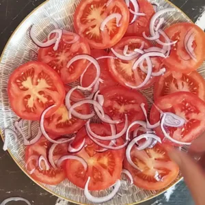 some sliced tomatoes on a plate with some sliced red onion.