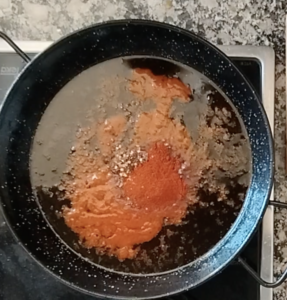 Tomato paste is added to hot oil in a large pan.