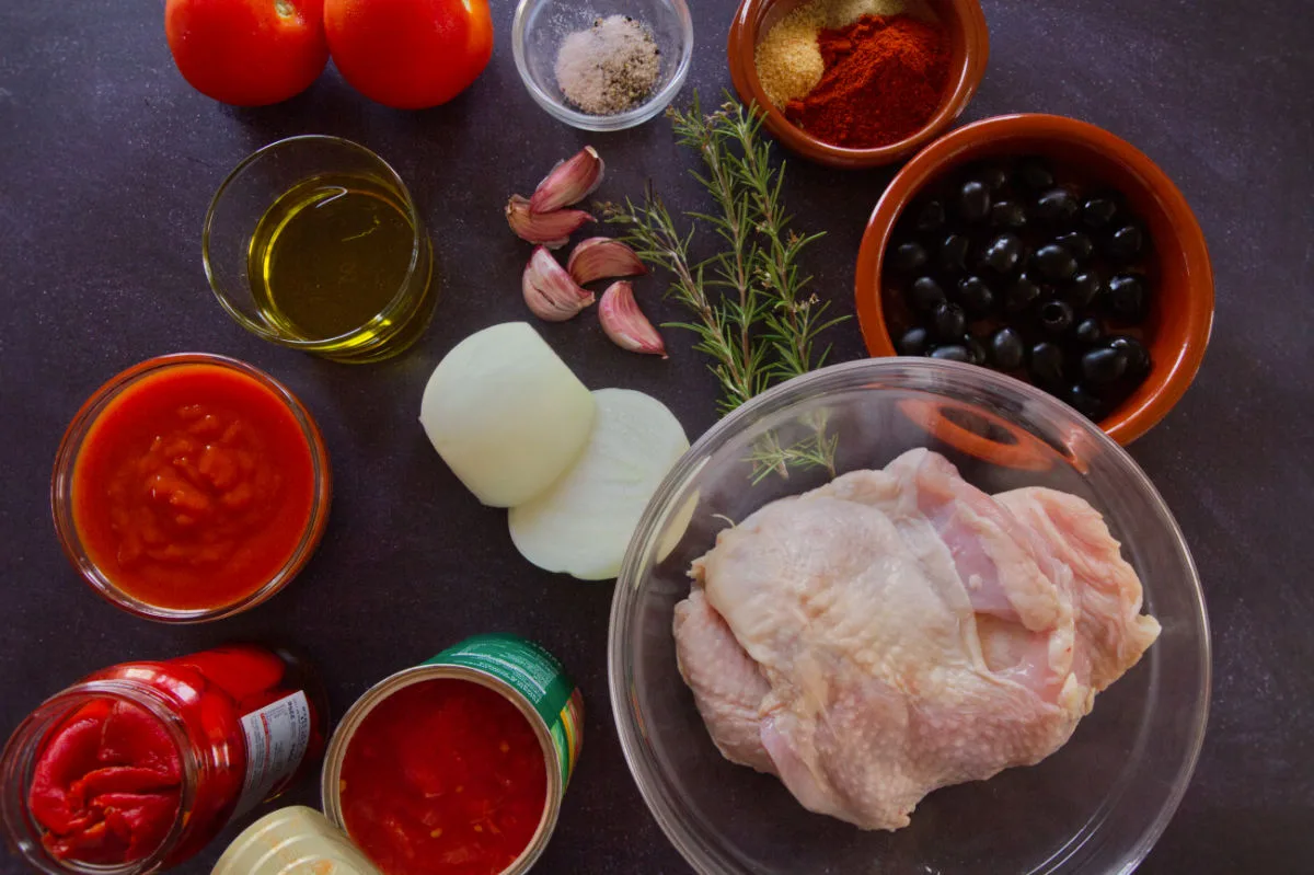 Ingedients used to make Mediterranean boneless chicken thighs and sofrito sauce are laid out on a kitchen table. 