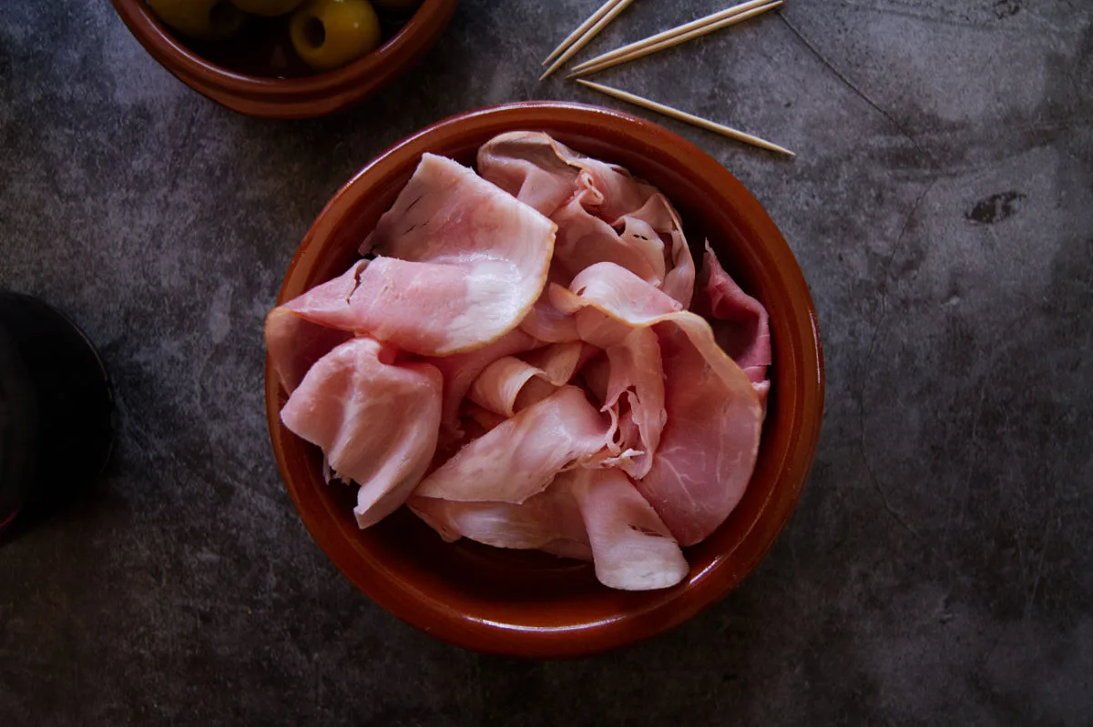 A small bowl of Spanish ham sits beside some toothpicks