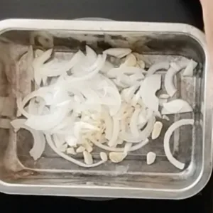 Chopped garlic and onion in a small baking pan.