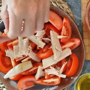 Tuna chunks are laid onto a bed of tomato wedges.