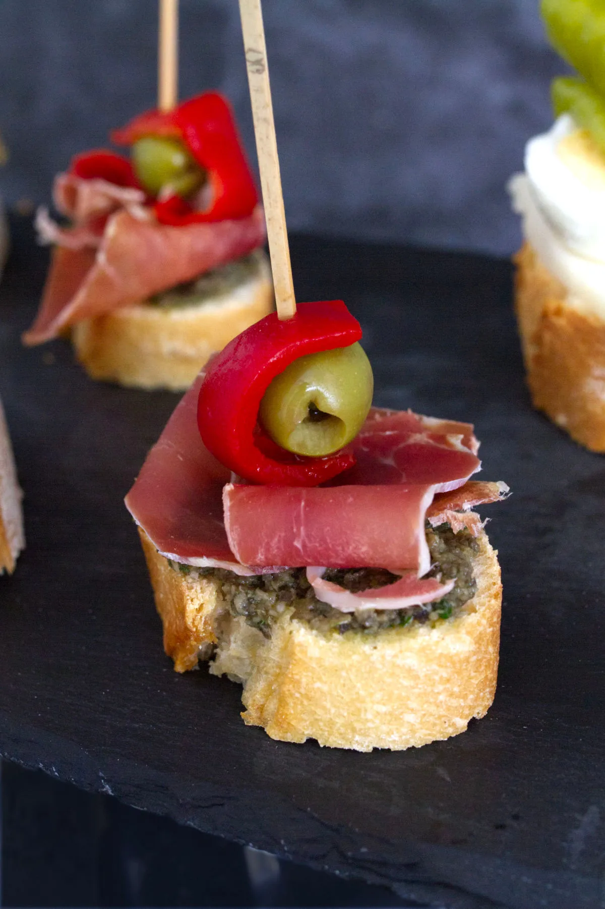 A ham and olive pintxos stacked on a slice of bread.