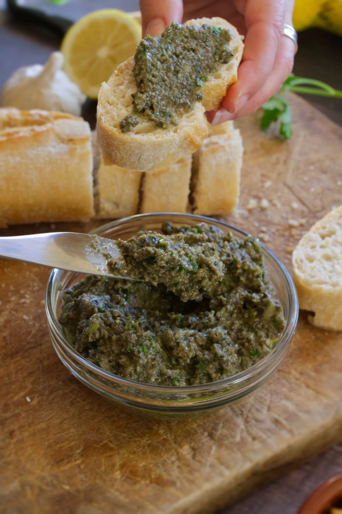 Some olive tapenade is served onto a slice of bread.