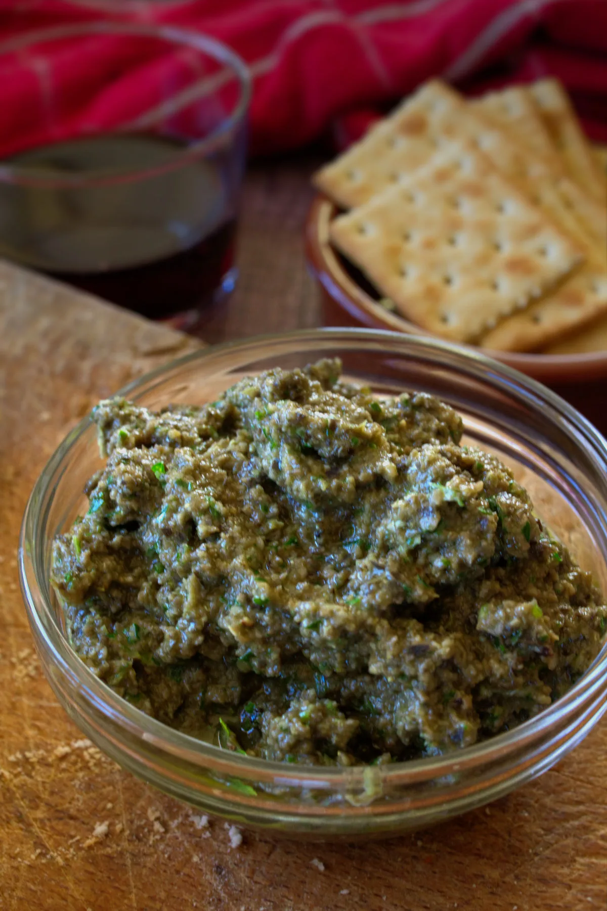 A bowl of Olive tapenade sits beside some crackers.