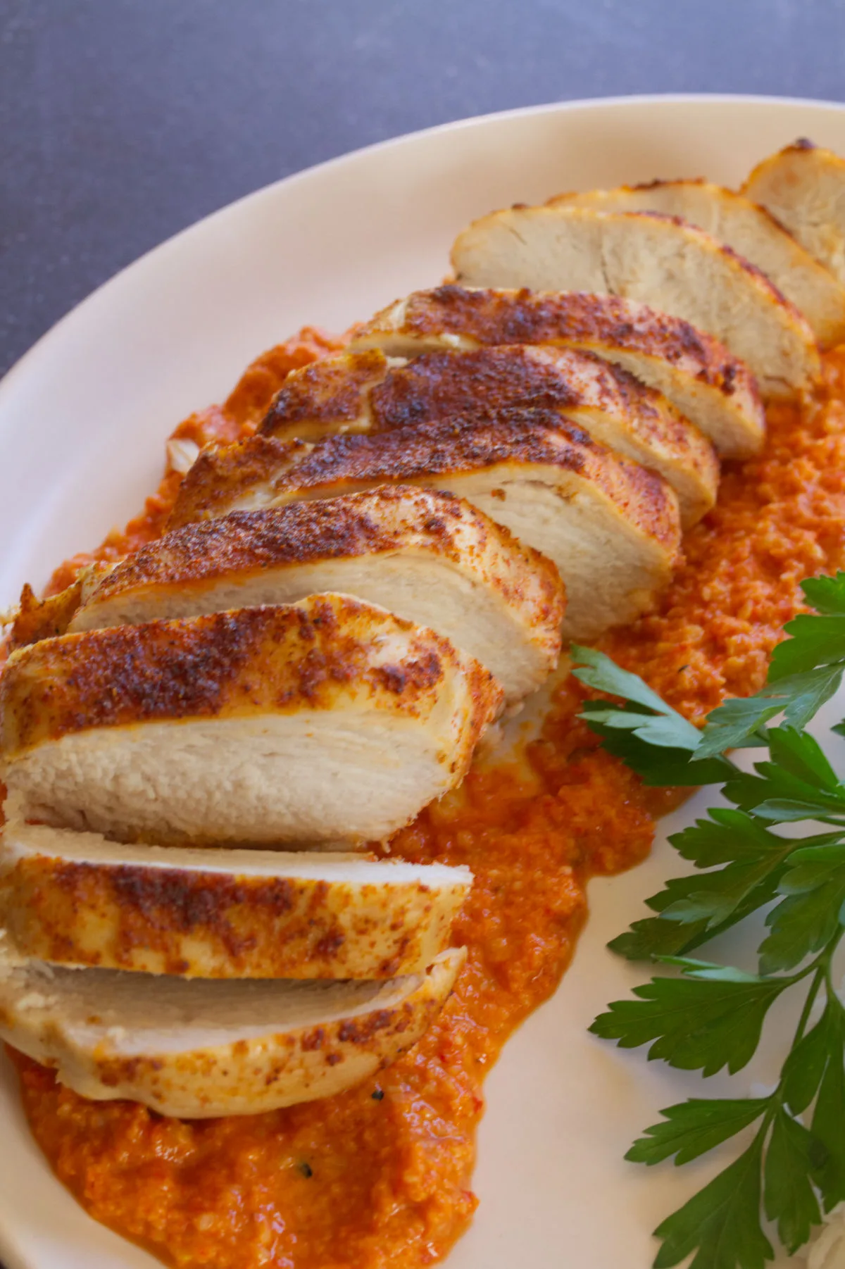 A plate fo sliced Roasted chicken breast with romesco sauce.