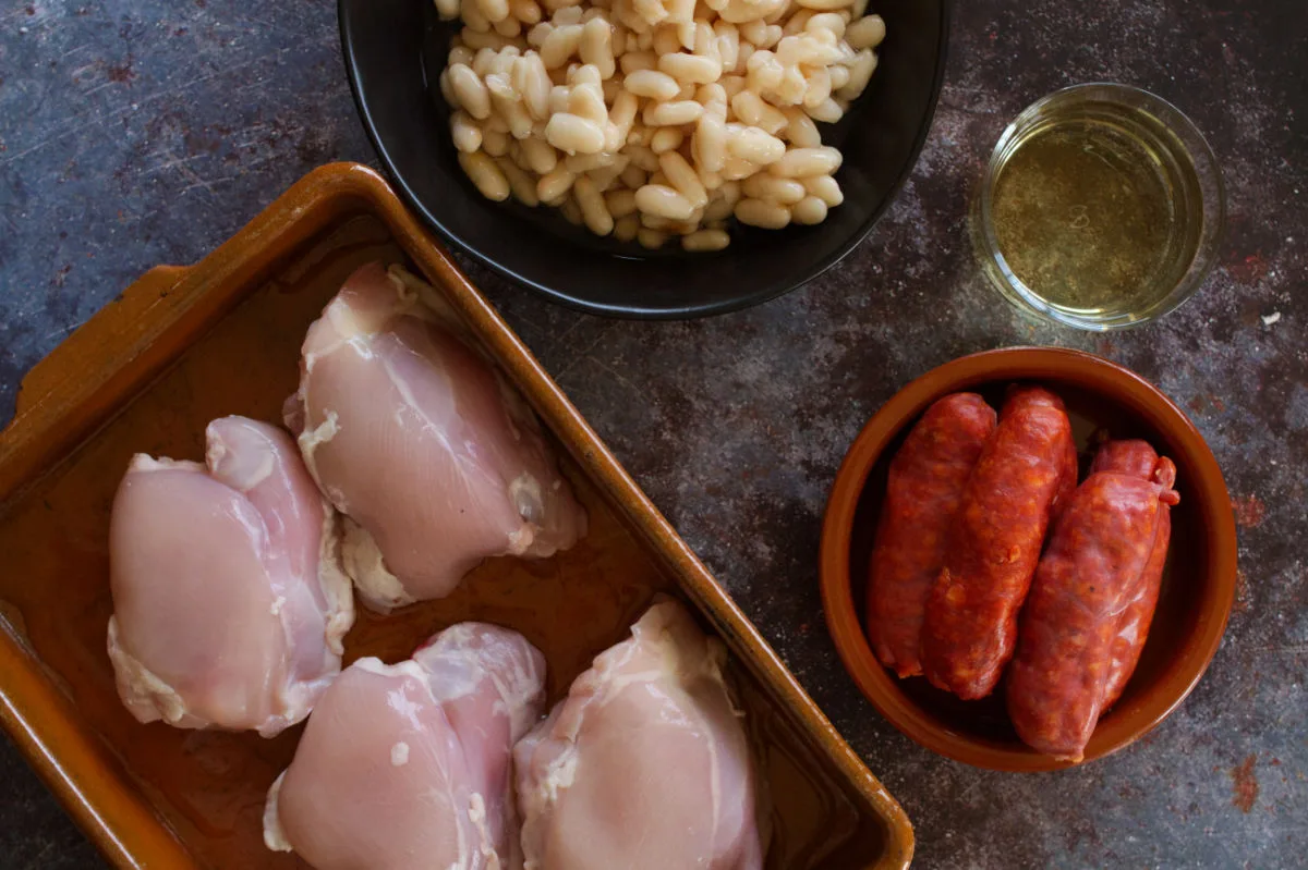 Chicken thighs sit beside some chorizo sausage, white beans, and sherry. 